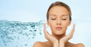 Woman with clear skin in front of a water splash background