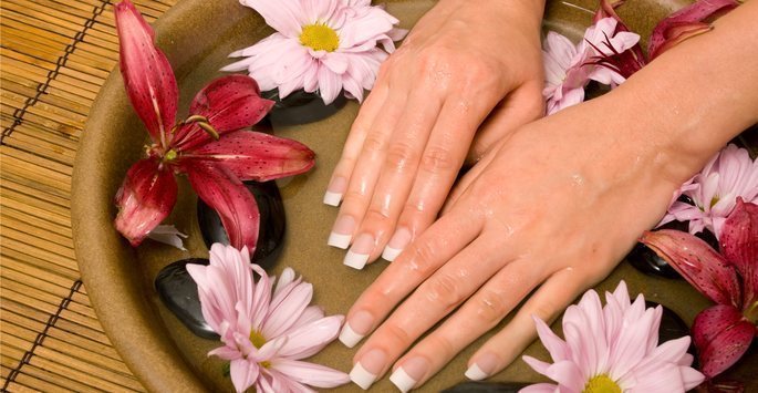 Smooth, wrinkle-free hands resting in a bowl with flowers