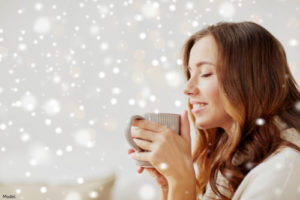 Cozy woman drinking a cup of hot coffee
