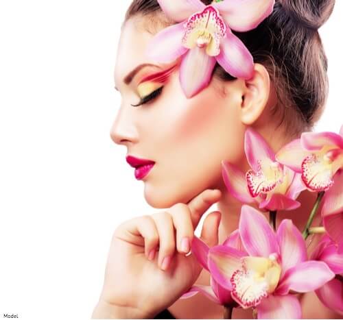 Serene woman looking off to the side covered in pink orchids