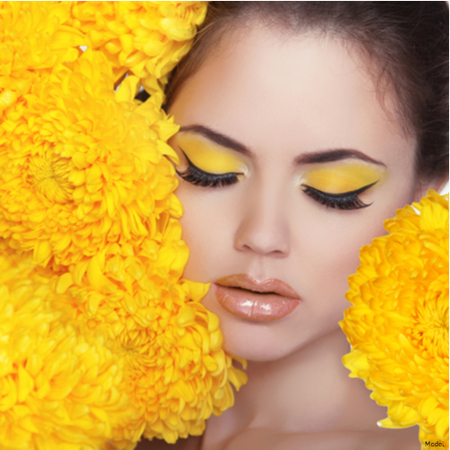 Woman in yellow eye makeup with yellow flowers around her