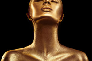Woman with skin covered in gold paint stretching her neck upwards