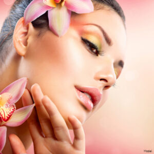 Relaxed woman with glowing skin surrounded by pink orchids