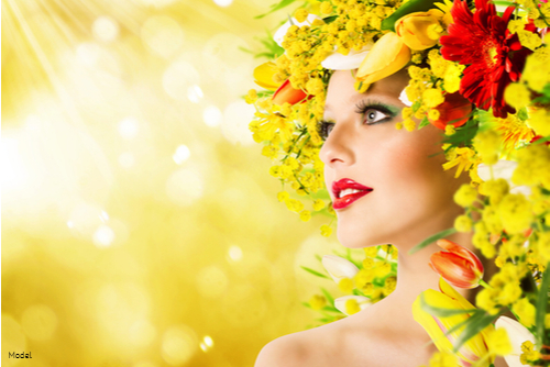 Woman surrounded by red and yellow flowers basking in sunlight