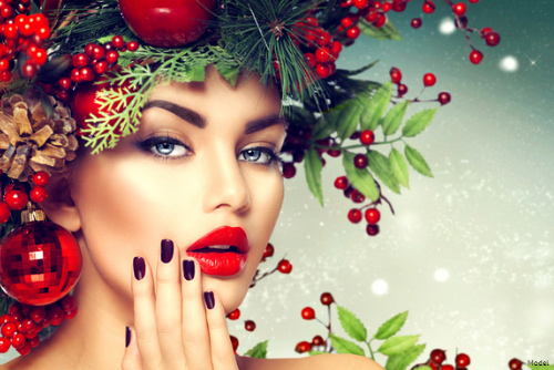 Stunning woman in red lipstick wearing a headdress of holly and leaves
