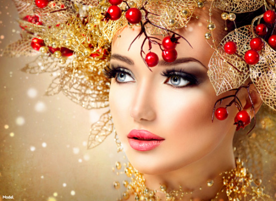 Woman in eye makeup surrounded by gold tinsel leaves and holly