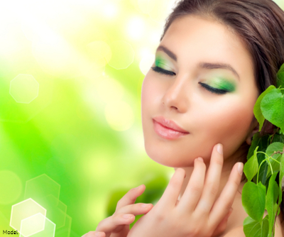Tranquil woman with green eye makeup gently touches her face