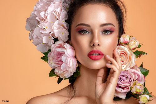 Woman with clear, bright skin in pink eye makeup with flowers in her hair