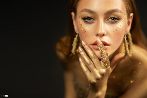 Stunning woman in gold glittery makeup gazing intensely